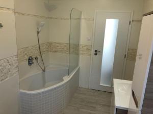 ein Badezimmer mit Badewanne und Glasdusche in der Unterkunft Luxusní apartmán přímo v centru u hotelu Thermal in Karlsbad