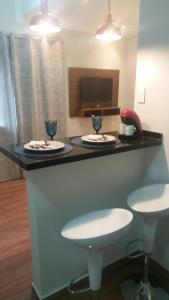 a counter with two plates and two glasses on it at Estúdio Praia residence in Santos