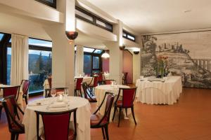 a restaurant with white tables and chairs and windows at Hotel dei Duchi in Spoleto