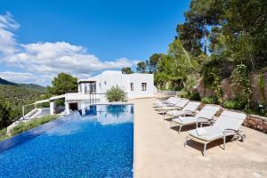 een zwembad met ligstoelen en een huis bij Villa Can Kiva in Es Cubells