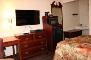 a hotel room with a bed and a dresser with a television at Battlefield Inn Springfield in Springfield
