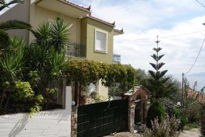 a yellow house with a black fence and plants at Beach Front House With View in Marathos