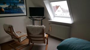 a bedroom with a bed and a chair and a window at Haus Ginkgo in Kappeln