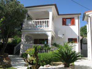 a white house with a balcony and some plants at Apartments and Rooms Lanča in Rab