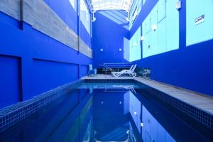 a swimming pool in a building with blue walls at Blue Open Hotel in Erechim