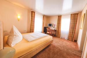 a hotel room with a bed and a desk at Hotel Löwen in Eggenstein-Leopoldshafen