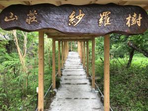 Una pasarela con un cartel con escritura asiática. en 山荘 紗羅樹 Syaranoki, en Yufu