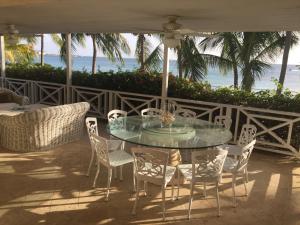 a glass table and chairs under an umbrella on a patio at Tantalus in Bridgetown