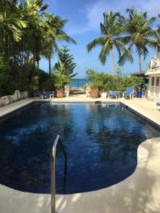 a swimming pool with palm trees and the ocean at Tantalus in Bridgetown
