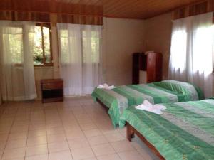 Zimmer mit 2 Betten und grüner Bettwäsche in der Unterkunft Cabinas Piuri in Rio Celeste