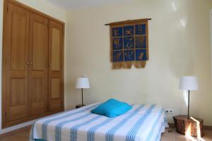Un dormitorio con una cama con una almohada azul encima. en Casa Água & Sal, en Praia Verde