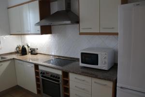 Una cocina con gabinetes blancos y un microondas en una encimera. en Casa Água & Sal, en Praia Verde