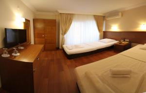a hotel room with two beds and a flat screen tv at Ucem Hotel Golden Sea in Altınoluk +61 photos