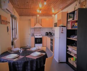 a kitchen with a table and a white refrigerator at Chacras de Coria desde Berdina casa loft privada para 4 con jardín, parrilla y cochera a 5 min a pie de la plaza principal in Chacras de Coria