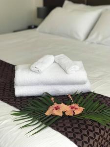 um quarto de hotel com toalhas e flores numa cama em The White House Hotel em Apia