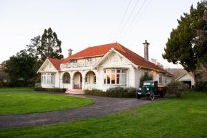 a house with a tractor parked in front of it at Corbett House Heritage Bed & Breakfast in Hikutaia
