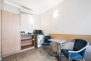 een kleine kamer met 2 stoelen, een tafel en een magnetron bij Welcome Inn 277 in Adelaide
