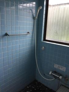 指宿市にある指宿中国民宿の窓付きのバスルーム(青いタイル張りのシャワー付)