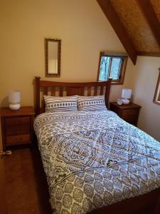 a bedroom with a bed with a blue and white comforter at Bundera Lodge in Vacy