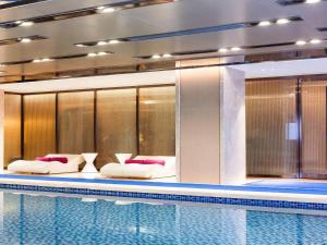 a swimming pool with two beds next to a poolasteryasteryasteryasteryasteryastery at Novotel Daqing Haofang in Daqing