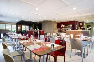 a dining room with tables and chairs in a restaurant at Campanile Rouen Est - Franqueville Saint Pierre in Franqueville-Saint-Pierre