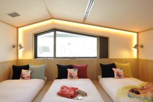 Duas camas num quarto com uma janela em CAFETEL Kyoto Sanjo for Ladies em Quioto