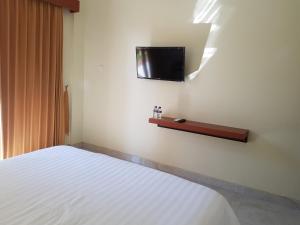 库塔Praba Guesthouse的卧室配有一张床,墙上配有电视。