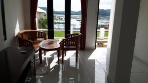 a dining room with a table and chairs and a window at Spear Beach House in Kuta Lombok