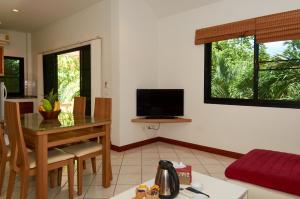 a living room with a table and a television at Phuket Riviera Villas - SHA Extra Plus in Nai Harn Beach