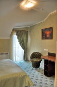 een slaapkamer met een bed, een stoel en een tafel bij Focus Hotel in Khust