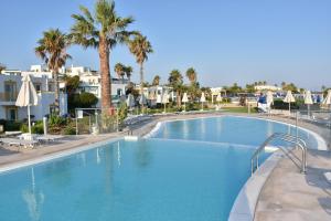 a large swimming pool with palm trees and houses at Mastichari Bay Hotel in Mastihari