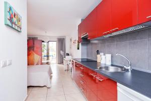 kuchnia ze zlewem i czerwonymi szafkami w obiekcie Popular Complex w mieście Los Cristianos