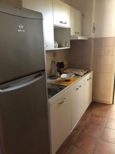 eine Küche mit einem Kühlschrank aus Edelstahl und weißen Schränken in der Unterkunft Oikos in Condofuri