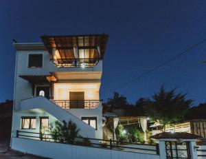 a large white building with a balcony at night at Lenti Street House in Kallirákhi
