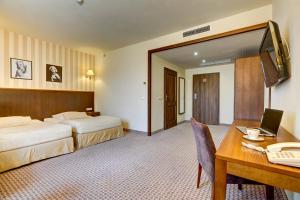 Pokój hotelowy z 2 łóżkami i biurkiem z laptopem w obiekcie Hotel Afrodyta Business & Spa w mieście Radziejowice