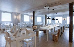 a restaurant with white tables and chairs and windows at Northern Light Hotell/Camp Steinfjord in Berg