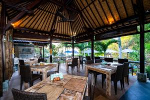 een openluchtrestaurant met houten tafels en stoelen bij Song Lambung Beach Huts in Nusa Lembongan