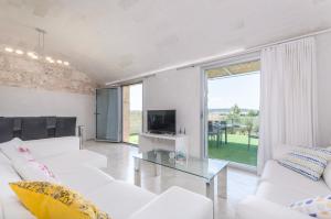 een woonkamer met witte banken en een televisie bij Es Gassons in Maria de la Salut