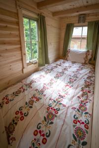 Ce lit se trouve dans une cabane en rondins dotée d'un couvre-lit floral. dans l'établissement Mount Hood Village Savannah Tiny House 4, à Welches