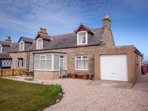 a large brick house with a white garage at The Mouries Holiday Cottage in Fochabers