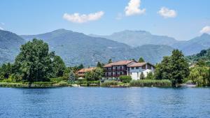 a house on a lake with mountains in the background at Cascina Tumas Orta Lake in Pettenasco