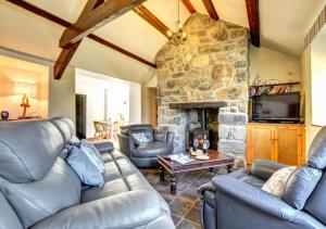 a living room with couches and a stone fireplace at Stabal Madrun in Abersoch