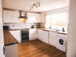 a kitchen with white cabinets and a washer and dryer at The Mouries Holiday Cottage in Fochabers