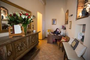 Bed & Breakfast Il Bargello في فلورنسا: امرأة تجلس في مكتب في غرفة مع إناء من الزهور