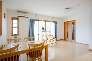 a dining room with a wooden table and chairs at JIYUKA INN in Izumi-Sano