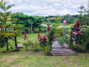 un sentiero in legno in un giardino con alberi e fiori di Panamma Hill Resort a Khao Kho