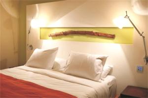 a bedroom with a bed with white pillows and a log on the wall at E-Hotel Larnaca Resort & Spa in Larnaka
