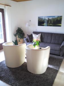 2 weiße Stühle im Wohnzimmer mit Sofa in der Unterkunft Haus Brandstaetter in Grundlsee