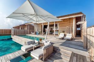a wooden deck with a pool and an umbrella at Kudadoo Maldives Private Island – Luxury All inclusive in Lhaviyani Atoll