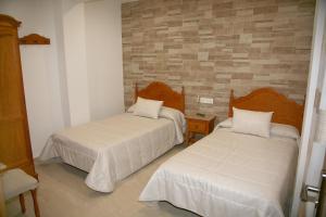 una camera da letto con due letti e un muro di mattoni di Hostal Restaurante Grela a Pozo Alcón Altre 3 foto